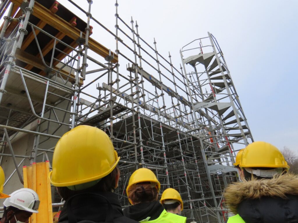Photo d'un groupe d'étudiants BUT GCCD en visite de chantier avec montage d'escalier et échafaudage