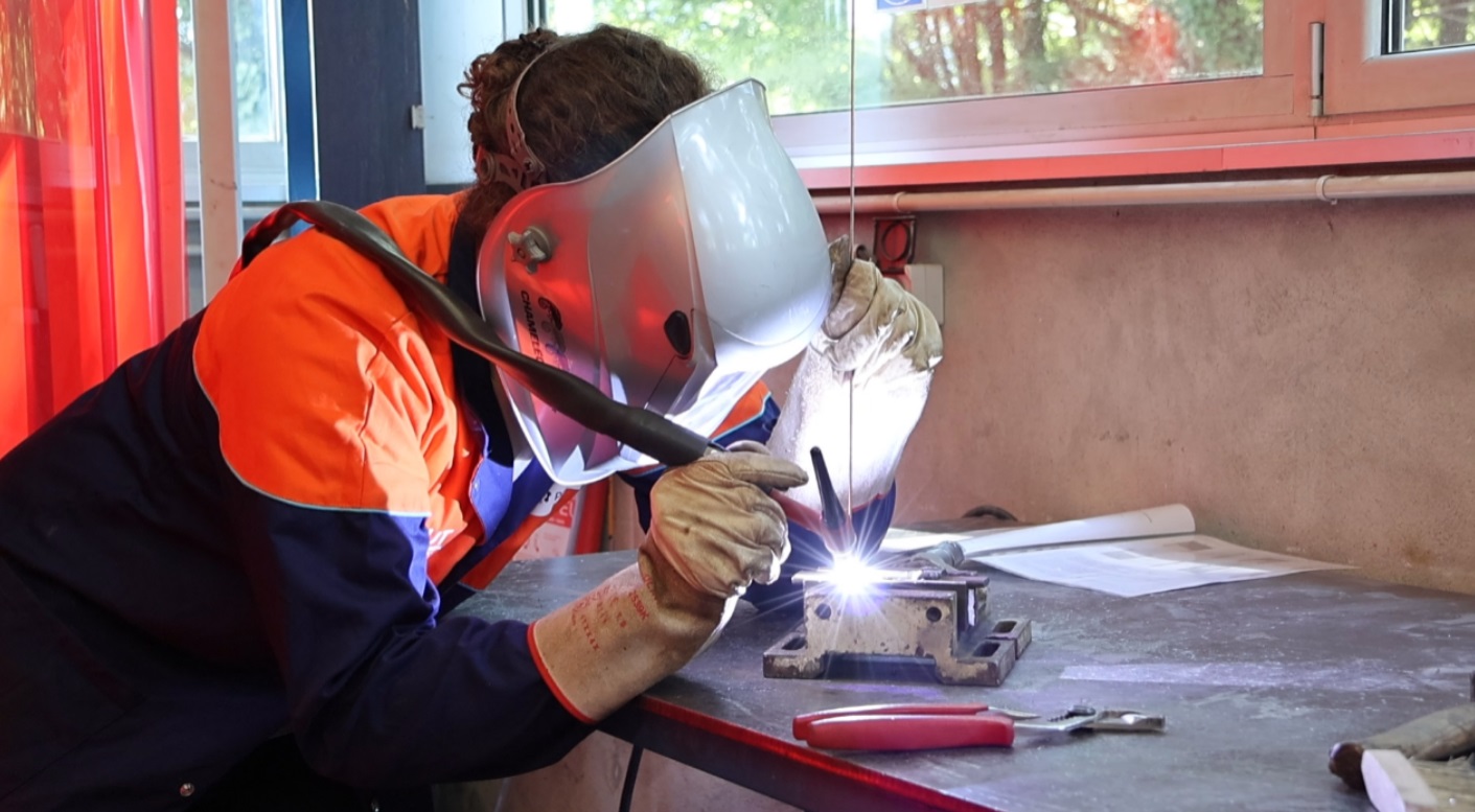 Photo d'une étudiante de BUT SGM ingénierie matériaux, en travaux pratiques de soudage à l'arc dans notre halle technique